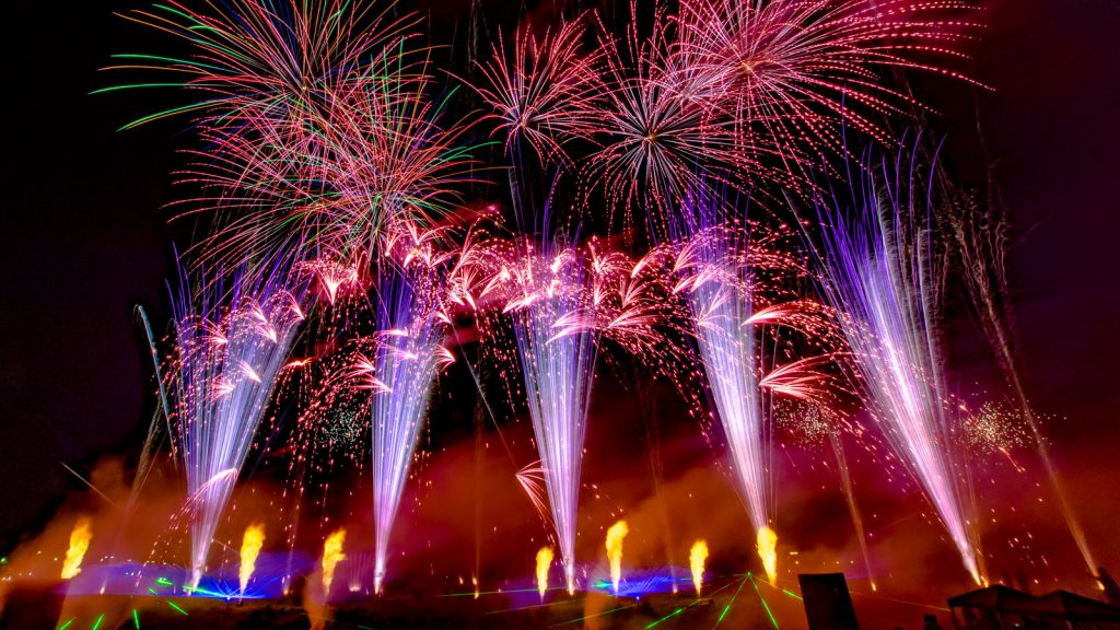 nico europe unternehmen company hoffest 2016 summer party 2016 flammen- und lasereffekte am boden, lila aufstiege zu rosa palmeneffekten, darüber viele bunte blink- und sterneffekte in grün, rot, blau, pink, orange